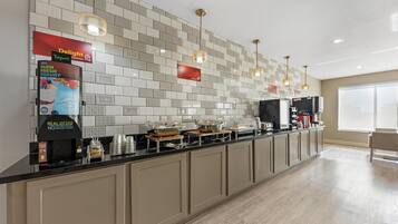 A modern kitchen with a long counter, various appliances, and a tiled backsplash.