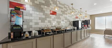 A modern kitchen with a long counter, various appliances, and a tiled backsplash.