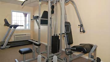 A gym with a variety of exercise equipment, including a bench press, a leg press, and a cable machine.