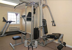 A gym with a variety of exercise equipment, including a bench press, a leg press, and a cable machine. - Days Inn by Wyndham Jasper TX (Jasper)
