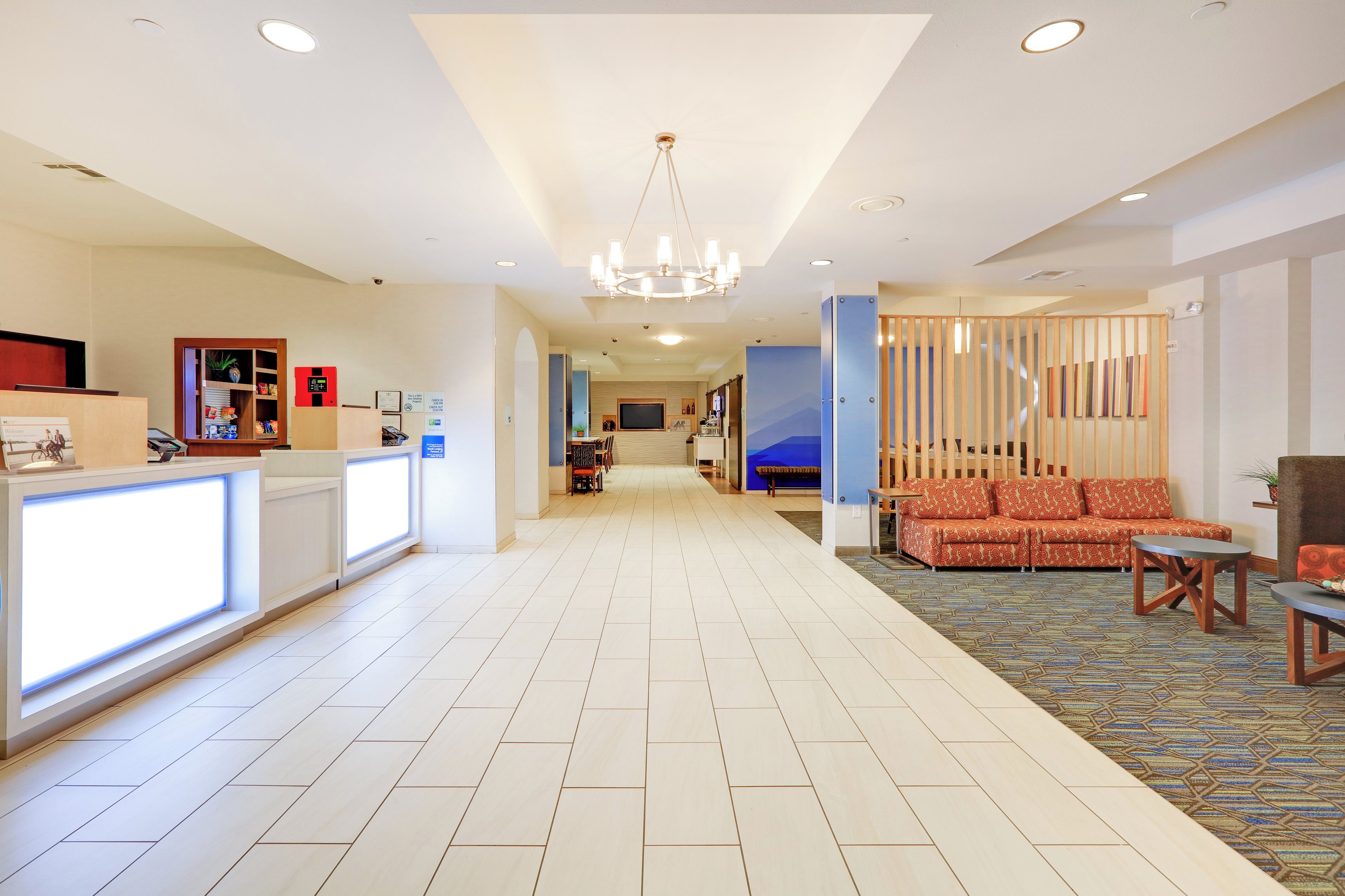 A hotel lobby with a reception desk, seating area, and a chandelier.