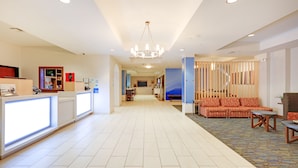 Een hotel lobby met een receptiebalie, een zithoek en een trap naar de bovenverdiepingen.