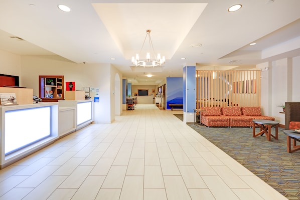 A hotel lobby with a reception desk, seating area, and a staircase leading to upper floors. - Holiday Inn Express & Suites Burleson/Ft. Worth by IHG (Burleson)