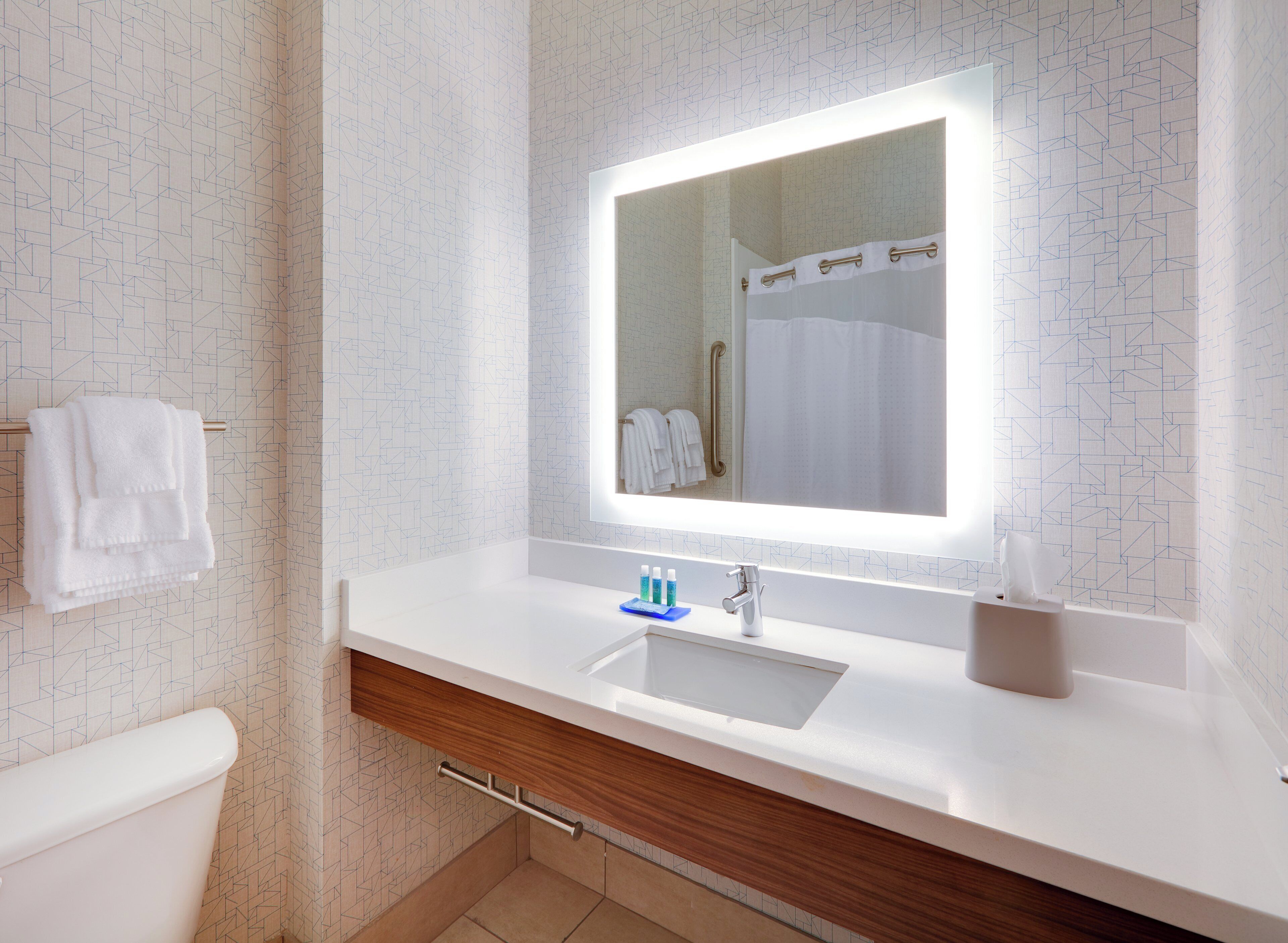 A modern bathroom with a white sink, a mirror, and a towel rack.