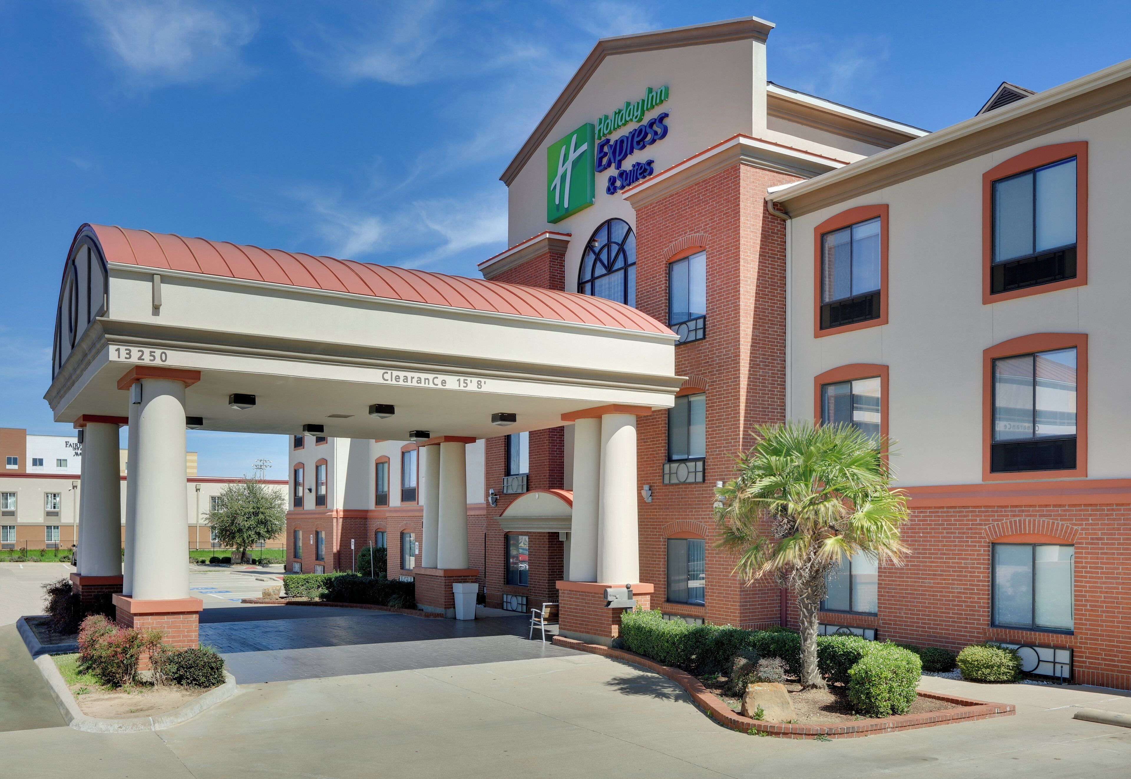 A Holiday Inn Express & Suites with a covered fuel pump and a brick facade.