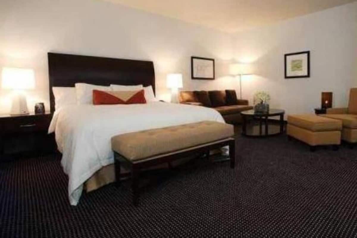 Ein Hotelzimmer mit einem großen Bett, einer Couch, einem Couchtisch und einem Schreibtisch mit Lampe.
