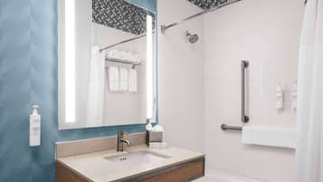 A modern bathroom with a sink, mirror, and shower.