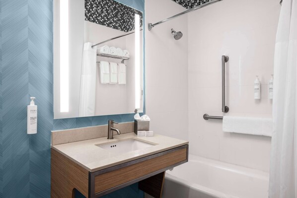 Un baño moderno con lavamanos, espejo y ducha.
