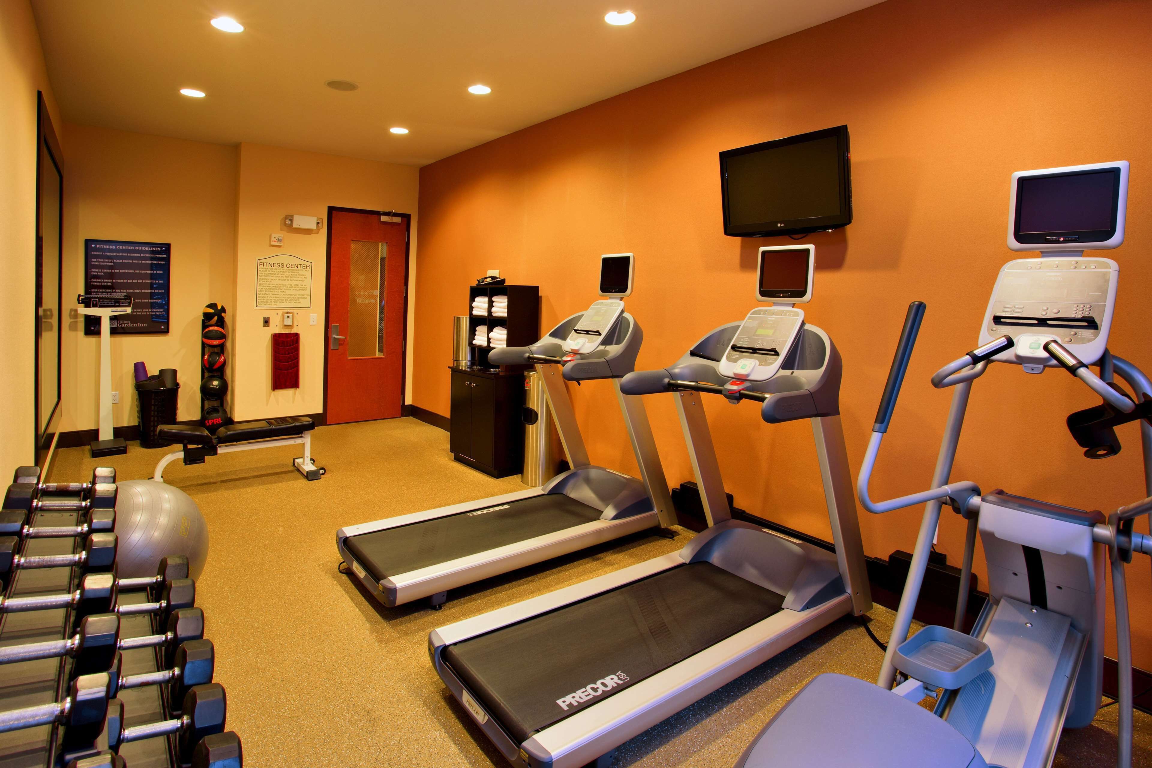 A fitness center with treadmills, dumbbells, and exercise balls.