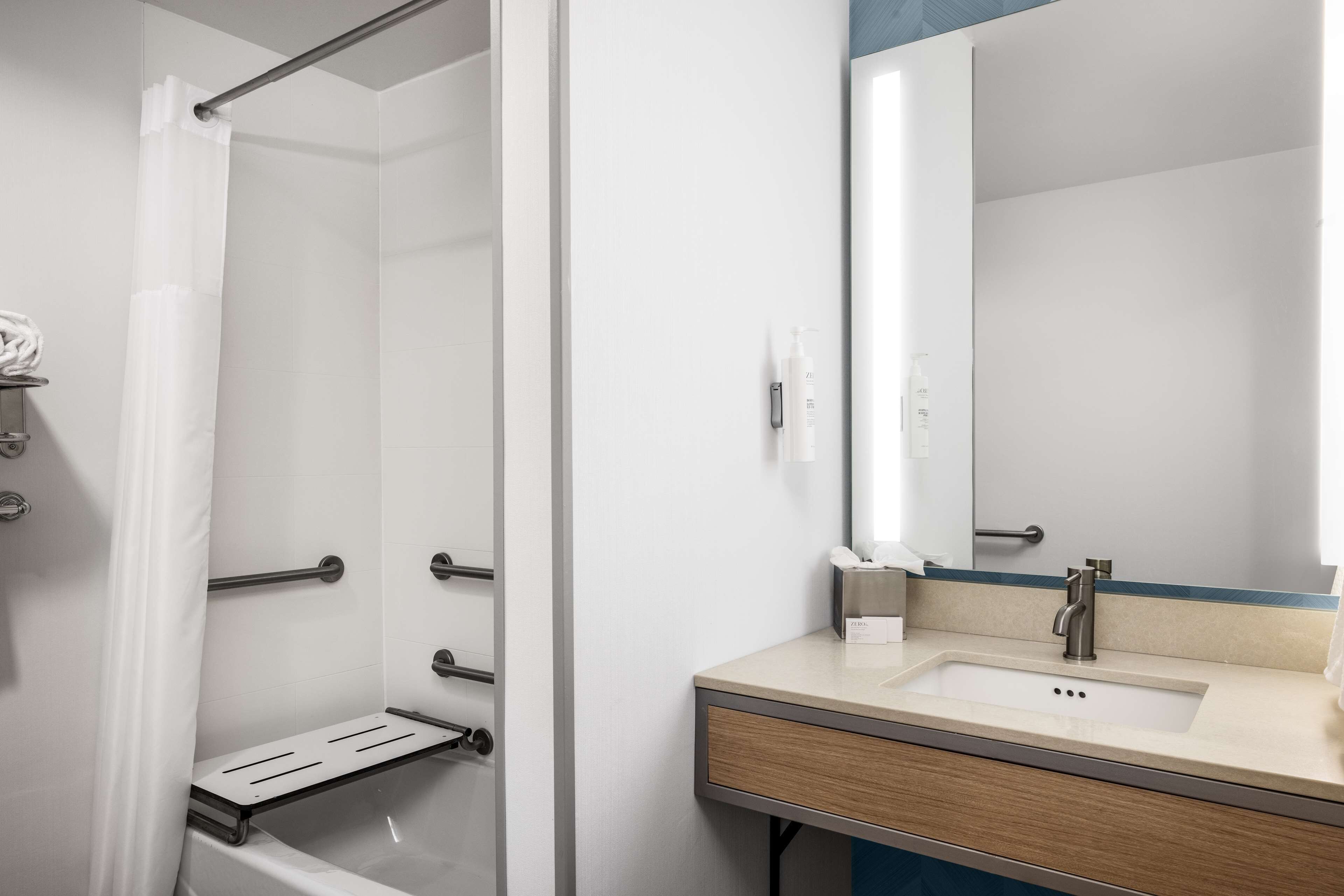 A modern bathroom with a shower, a sink with a mirror, and a towel rack.