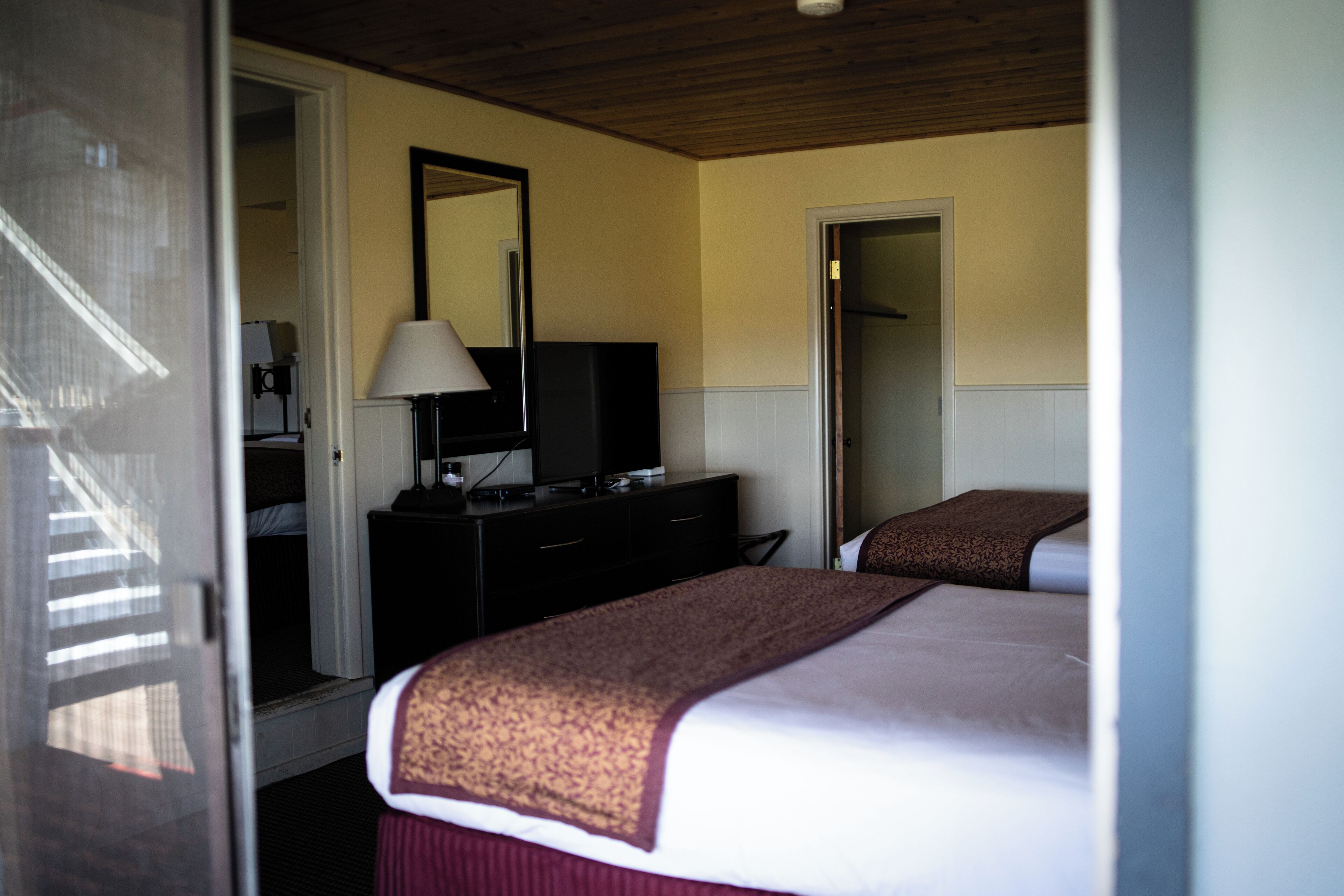 Quarto de hotel com uma cama, uma televisão em uma cômoda e um espelho na parede.