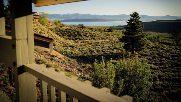 A view from a balcony overlooking a hilly landscape with a body of water and mountains in the distance. - Yosemite Gateway Motel (Lee Vining)