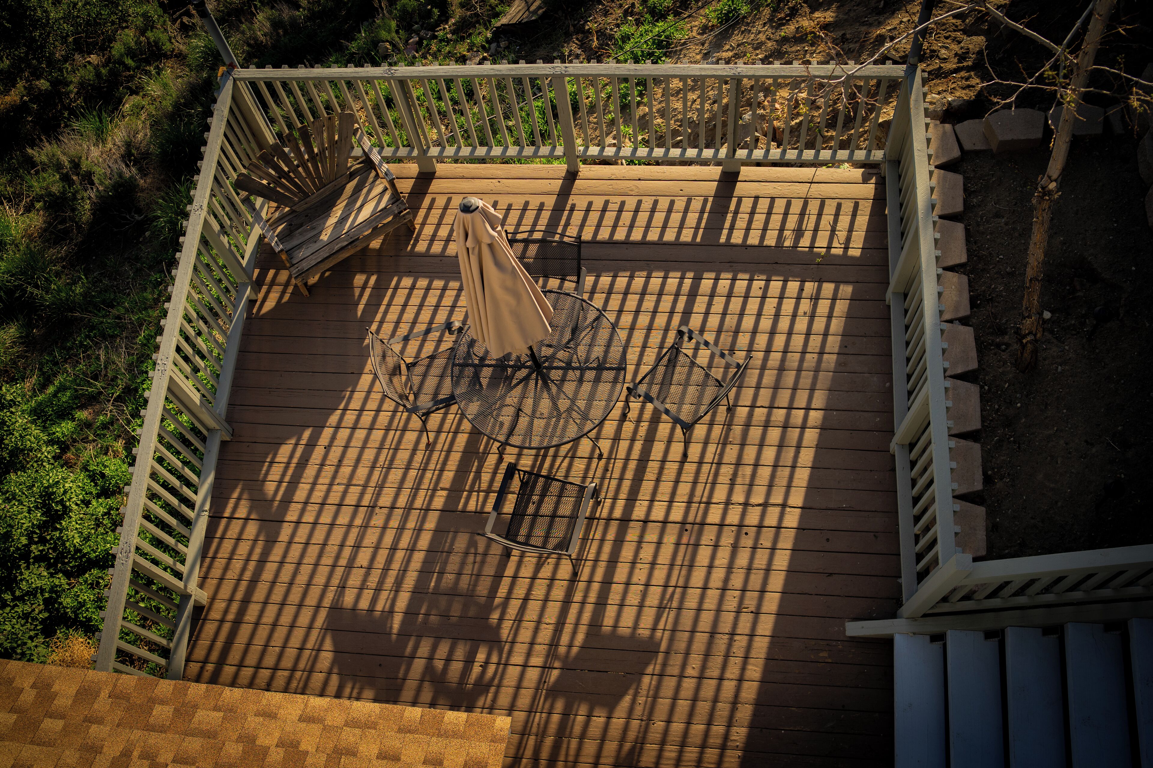 A wooden deck with a metal table and chairs, surrounded by a white railing.