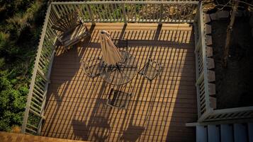 A wooden deck with a metal table and chairs, surrounded by a white railing.