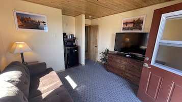 A living room with a sofa, a coffee table, a TV, a cabinet, and a door.