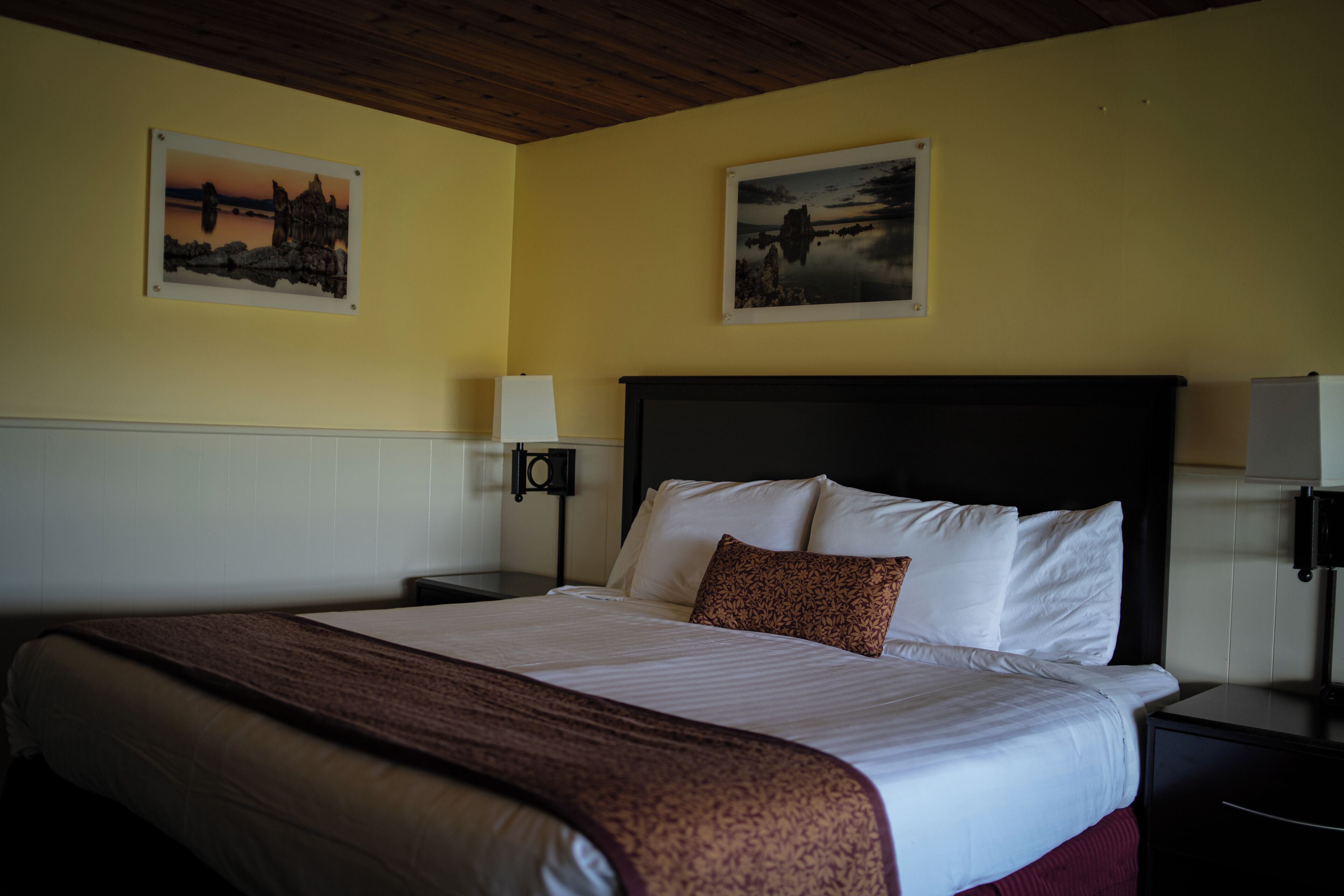 Camera d'albergo con un letto grande, due comodini, due lampade a parete e due quadri appesi alle pareti.