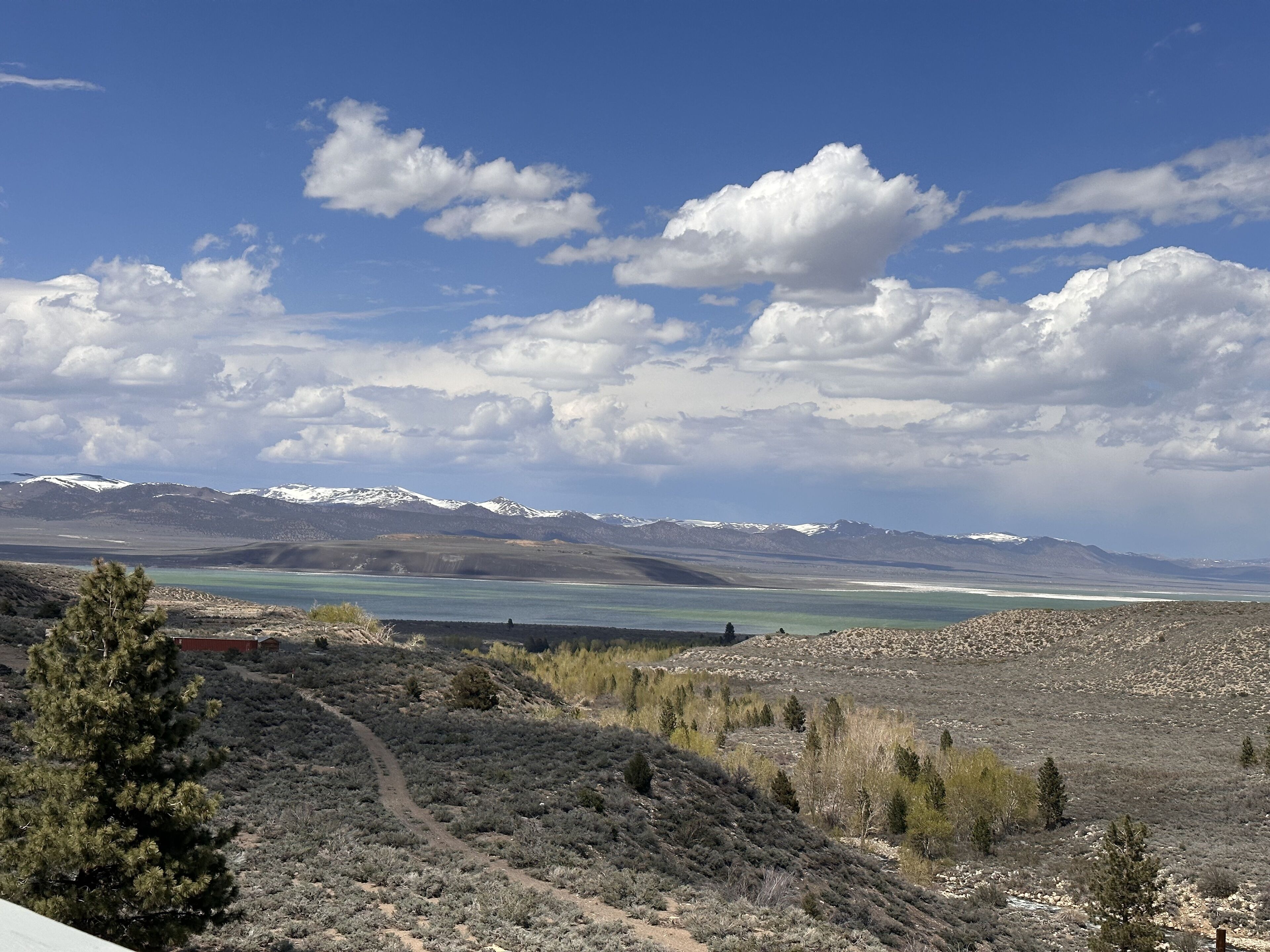 A mountainous landscape with a clear sky, a lake, and sparse vegetation.