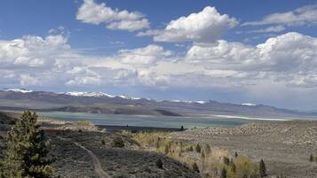 A mountainous landscape with a clear sky, a lake, and sparse vegetation.