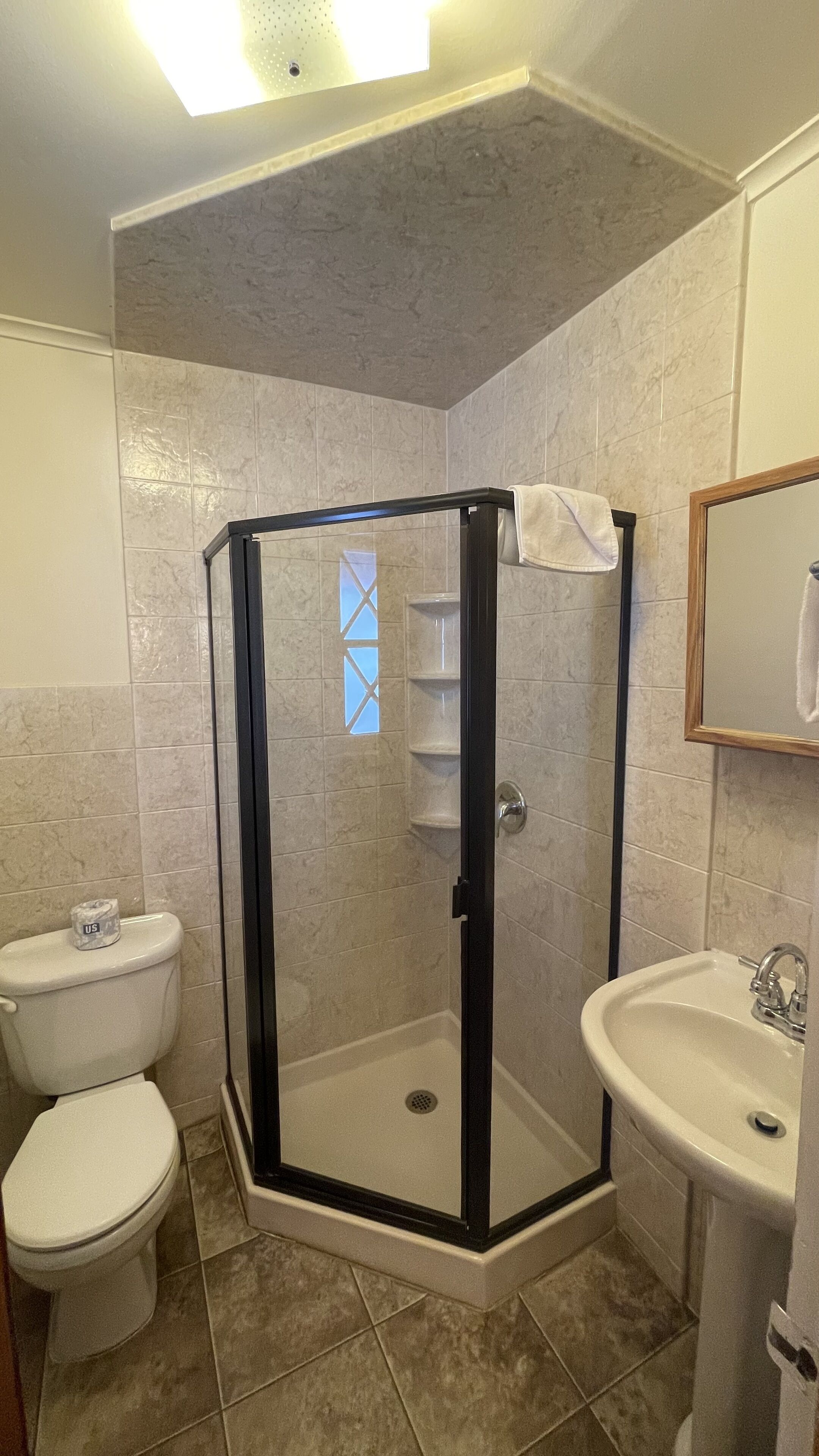 A bathroom with a glass-enclosed shower, a toilet, and a sink.