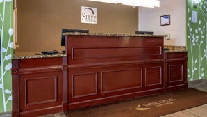 Un comptoir d’accueil avec une enseigne indiquant « Sleep Inn & Suites », un ordinateur et un certificat encadré accroché au mur.