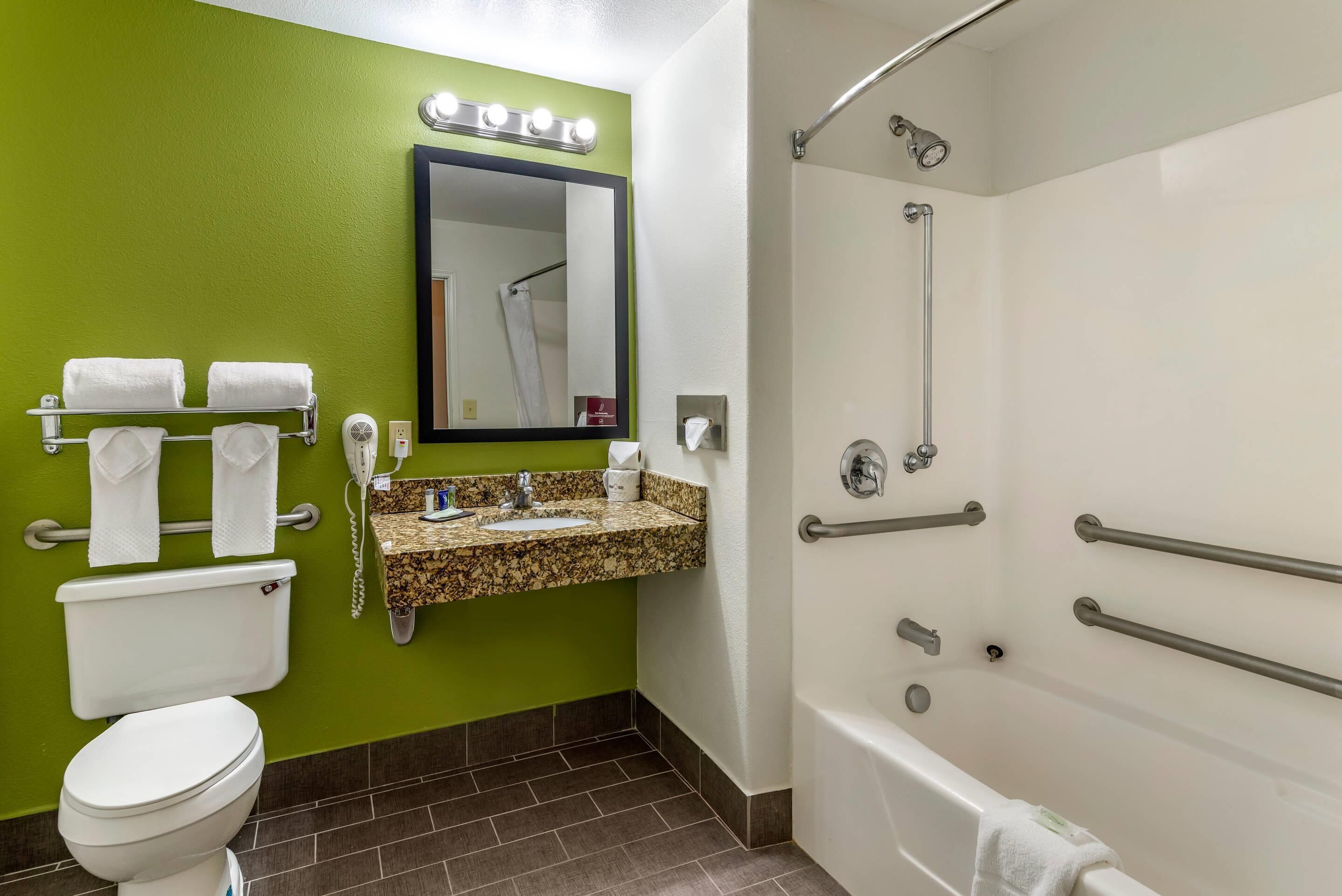 A bathroom with a toilet, sink, mirror, and shower.