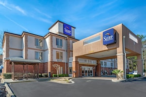 A Sleep Inn & Suites building with a covered entrance, brick facade, and a clear blue sky.