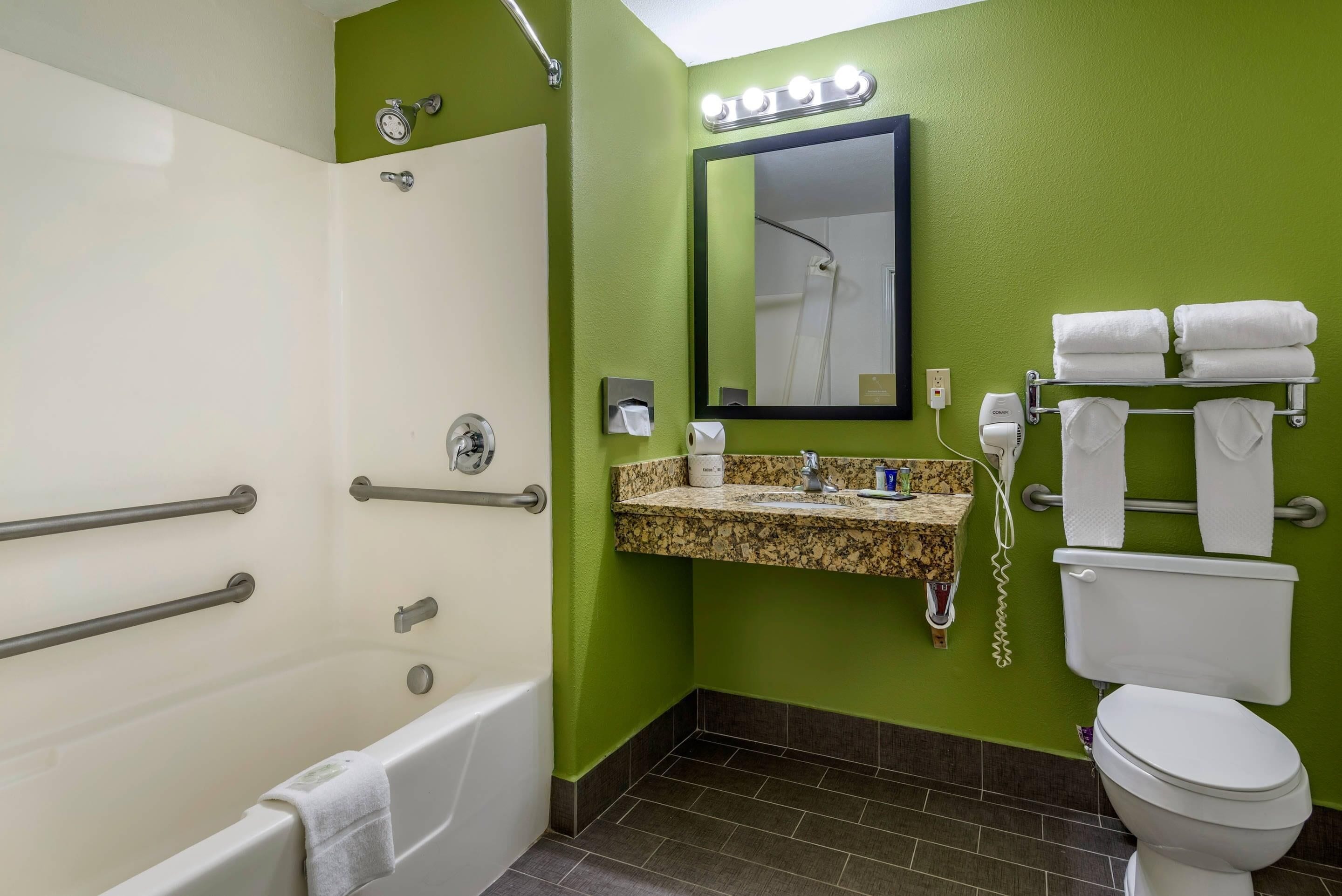 Un baño con bañera, lavabo con espejo e inodoro.