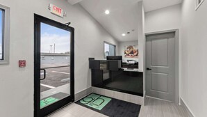A hotel reception area with a reception desk, a large window, and an exit sign. - GuestHouse Extended Stay Laredo (Laredo)