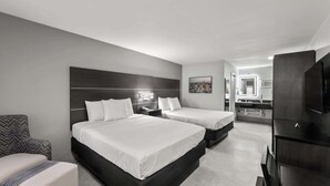 A hotel room with two beds, a sofa, a TV, and a kitchenette. - GuestHouse Extended Stay Laredo (Laredo)