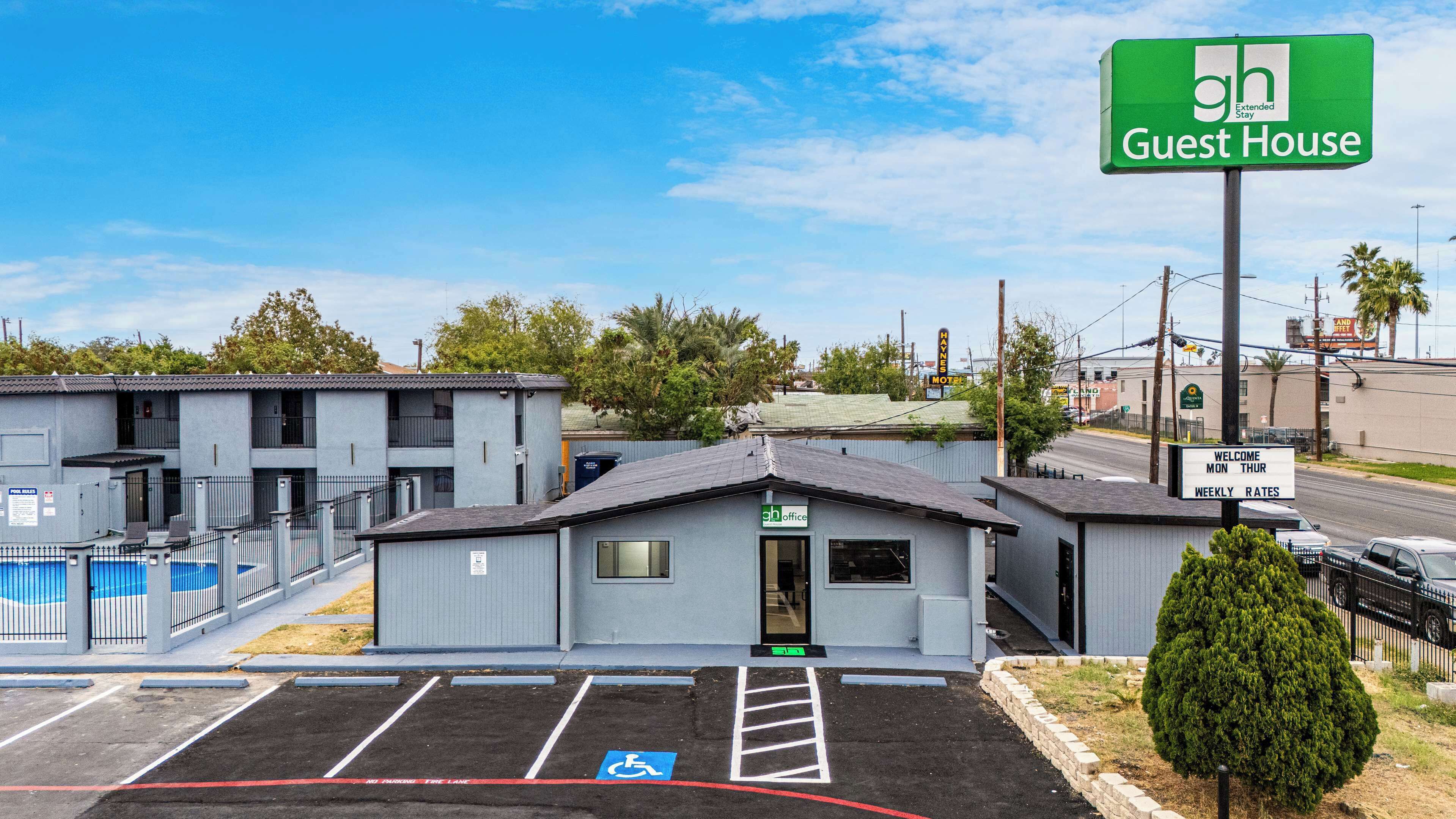 A guest house with a sign indicating weekly rates, a pool, and a parking lot with a handicapped accessible space.