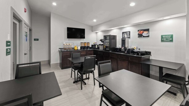 A modern kitchen with a dining area, equipped with a refrigerator, microwave, and coffee machine. There are signs indicating breakfast availability. - GuestHouse Extended Stay Laredo (Laredo)