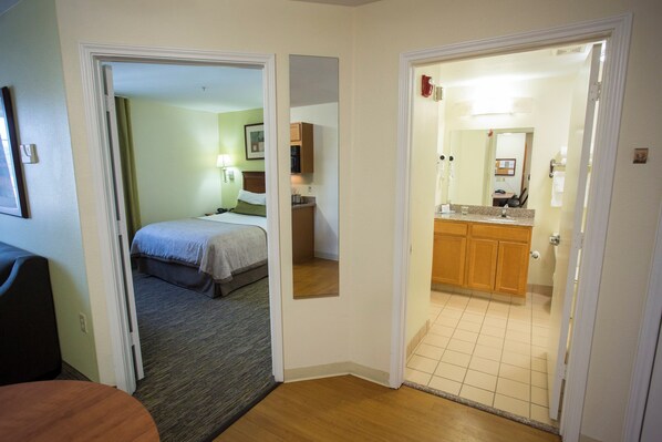 Habitación de hotel con una cama, un escritorio pequeño y un baño visible a través de una puerta abierta.