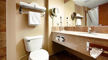 Un baño moderno con inodoro, lavamanos y dos espejos. Hay toallas y un secador de pelo en la pared.