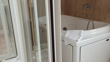 Un baño con bañera, ducha y puerta de vidrio para la ducha.