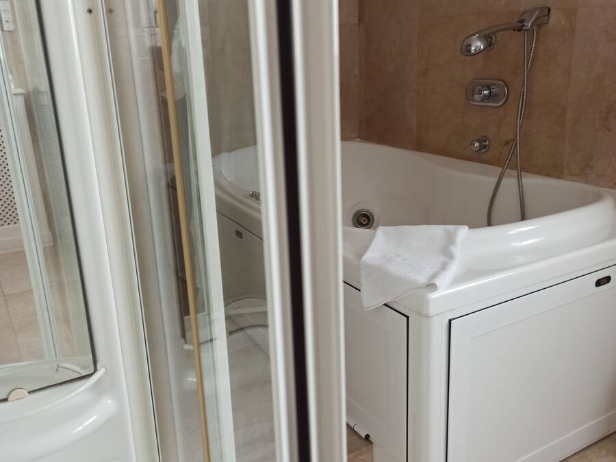 Un baño con bañera, ducha y puerta de vidrio para la ducha.