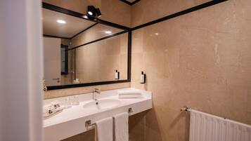 A modern bathroom with a large mirror, a white sink, and a towel rack.