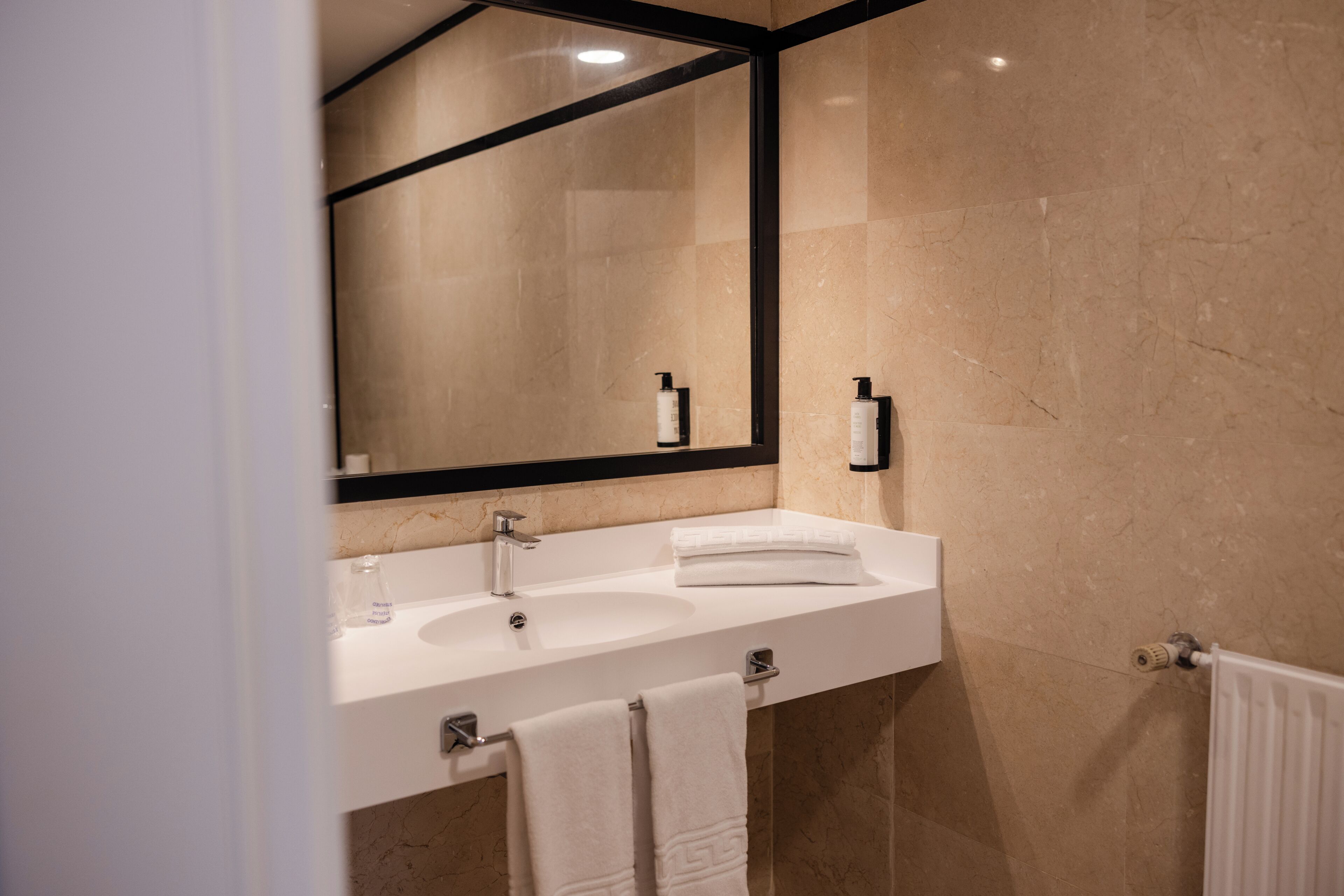 A bathroom with a white sink, a mirror, and a towel rack.