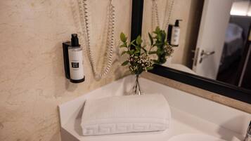 A bathroom with a white sink, a towel, a mirror, and a wall-mounted phone.