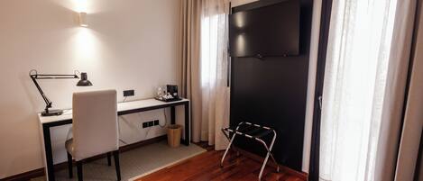 A modern room with a desk, chair, TV, and a standing stool.