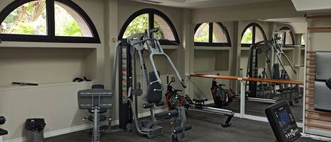 A gym with exercise equipment, large windows, and a mirror.