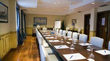 A conference room with a long table, white chairs, and a projector screen.