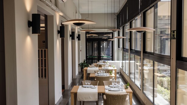 A long dining area with tables set for meals, large windows, and hanging pendant lights. - Hotel Escuela Santa Brígida (Santa Brigida)