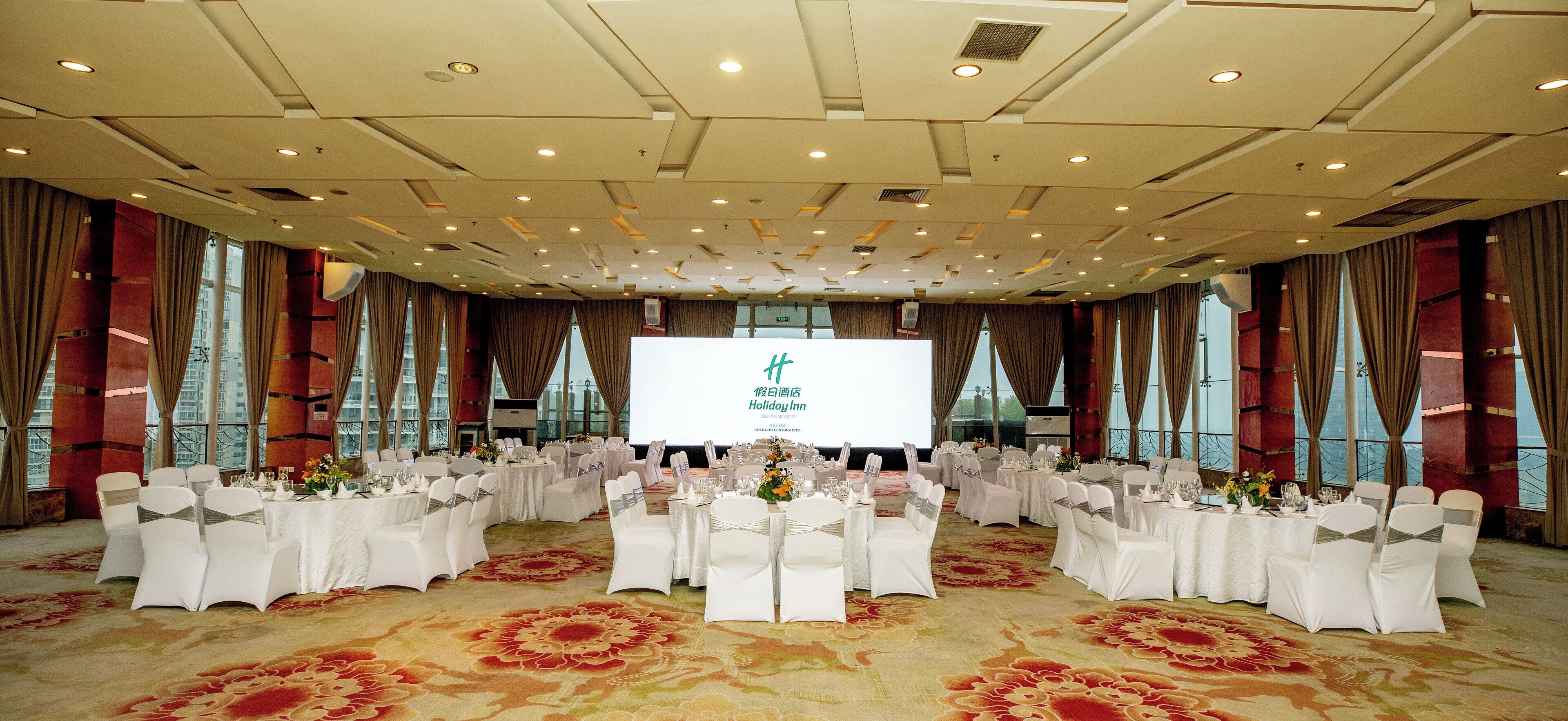 A banquet hall with round tables, white tablecloths, and chairs with sashes.