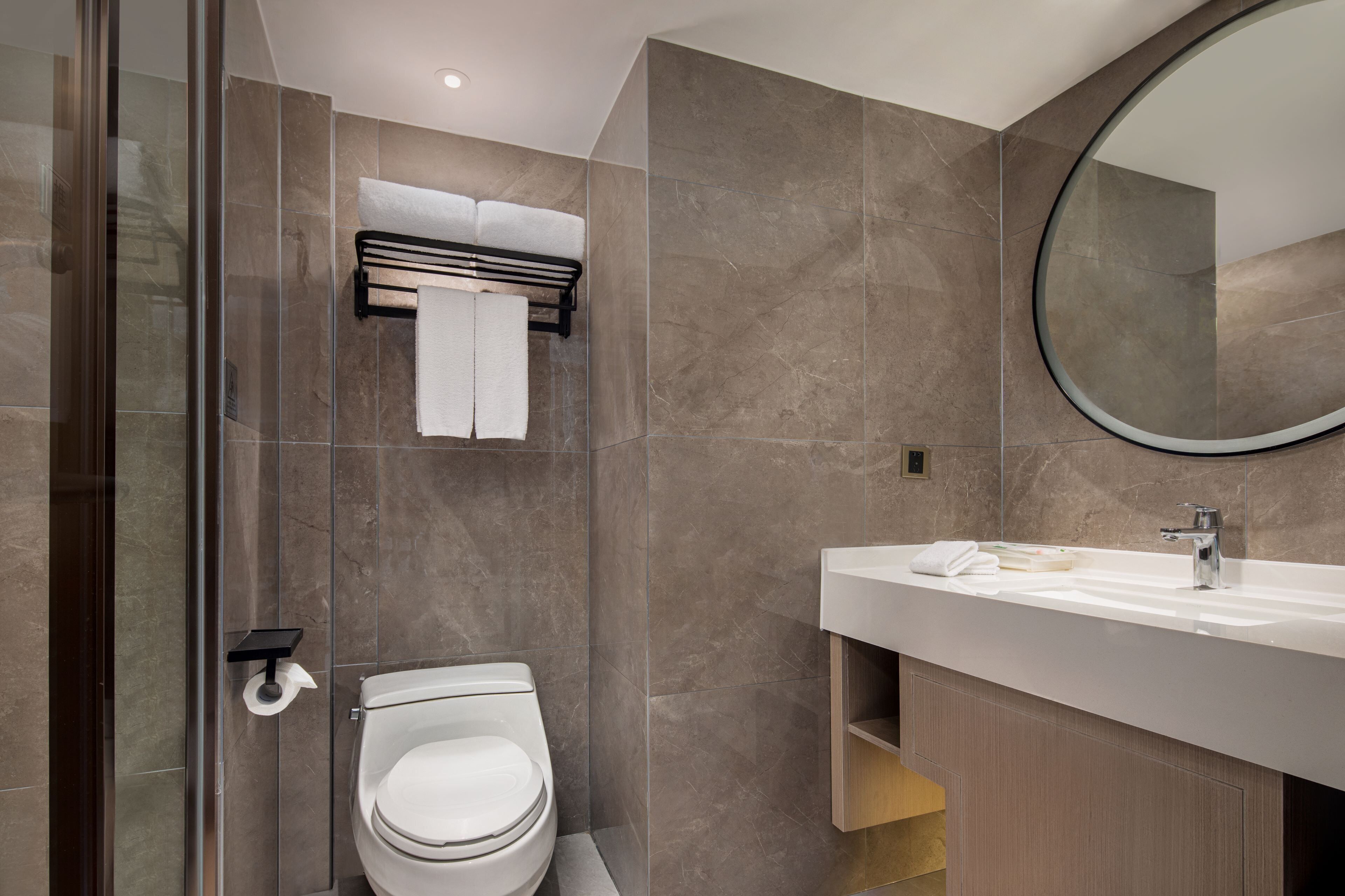 A modern bathroom with a toilet, a sink, and a mirror.
