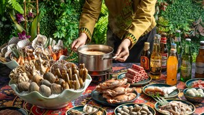A table with various seafood dishes, bottles of beer, and a person cooking. - Holiday Inn Chengdu Century City-WestTower by IHG (Chengdu)