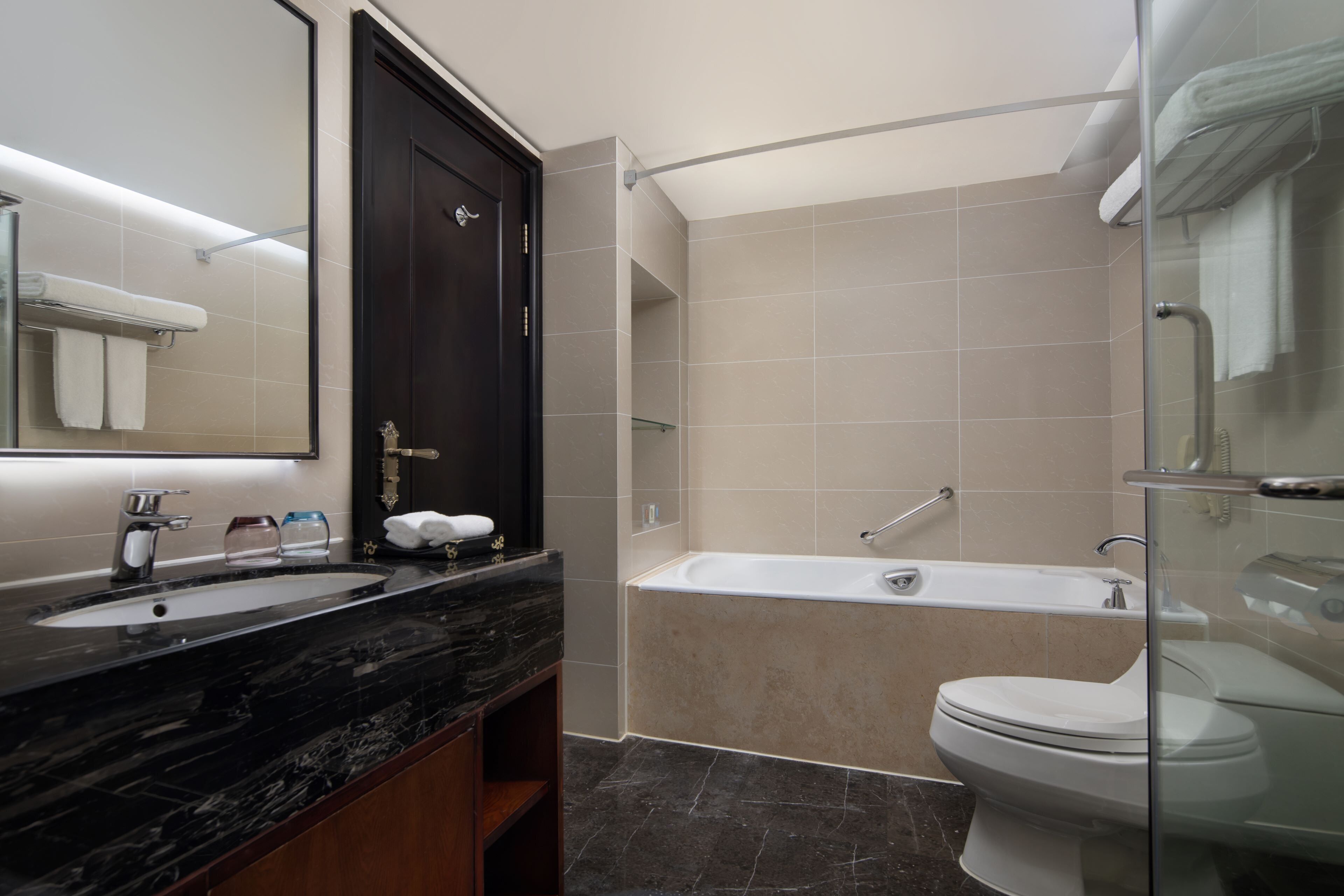 A modern bathroom with a double sink, a bathtub, and a toilet.