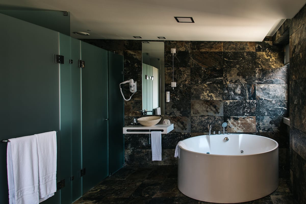 A modern bathroom with a freestanding bathtub, a vanity with a bowl sink, and a mirror above the sink.