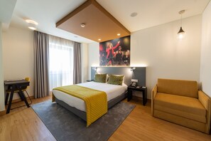 Una habitación de hotel moderna con cama, mesita de noche, silla y un cartel grande en la pared.