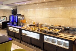 Montaje de bufé con diferentes opciones de comida y una estación de café.
