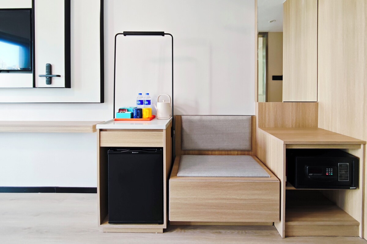 A compact hotel room with a kitchenette, a small refrigerator, a microwave, and a flat-screen TV.